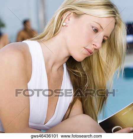 Side profile of a young woman reading a book at the poolside View Large Photo Image Stock Image - Side profile of a young woman reading a book at the poolside. Fotosearch