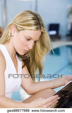 Side profile of a young woman reading a book at the poolside View Large Photo Image Stock Photo - Side profile of a young woman reading a book at the poolside. Fotosearch