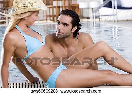 Side profile of a young woman sitting at the poolside with a mid adult man in the swimming pool View Large Photo Image Stock Photo - Side profile of a young woman sitting at the poolside with a mid adult man in the swimming pool. Fotosearch