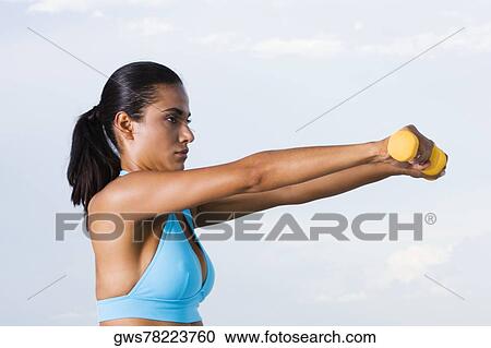 Side profile of a young woman exercising with dumbbells View Large Photo Image Stock Image - Side profile of a young woman exercising with dumbbells. Fotosearch