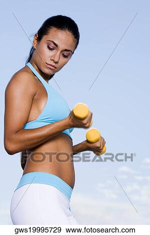 Side profile of a young woman exercising with dumbbells View Large Photo Image Stock Photo - Side profile of a young woman exercising with dumbbells. Fotosearch