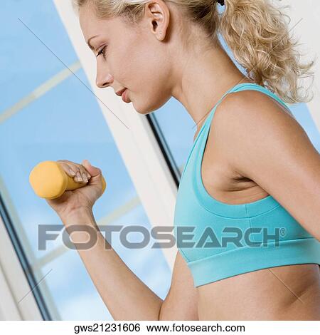 Side profile of a young woman exercising with a dumbbell View Large Photo Image Stock Photograph - Side profile of a young woman exercising with a dumbbell. Fotosearch
