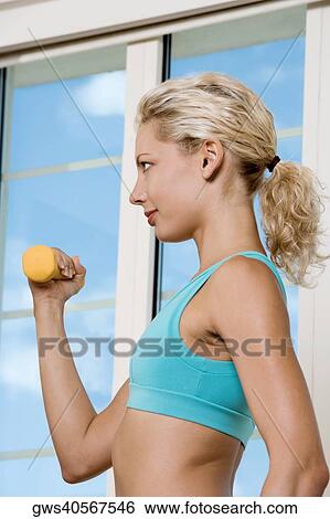 Side profile of a young woman exercising with dumbbells View Large Photo Image Stock Photograph - Side profile of a young woman exercising with dumbbells. Fotosearch