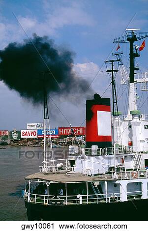 Stock Image - Smoke pollution freighter, Saigon river, Vietnam. Fotosearch