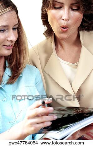 Two secretaries looking at a note pad View Large Photo Image Picture - Two secretaries looking at a note pad. Fotosearch