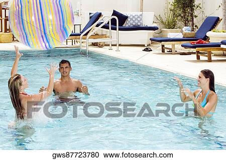 Two young women and a young man playing with a beach ball in a swimming pool View Large Photo Image Stock Image - Two young women and a young man playing with a beach ball in a swimming pool. Fotosearch