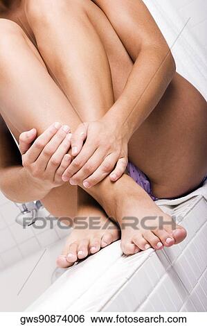 Stock Photograph - Woman sitting at the edge of a bathtub. Fotosearch