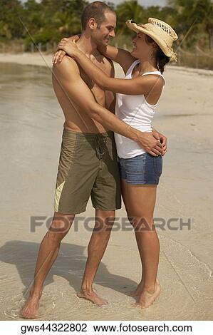 Stock Image - Young couple embracing each other on the beach. Fotosearch