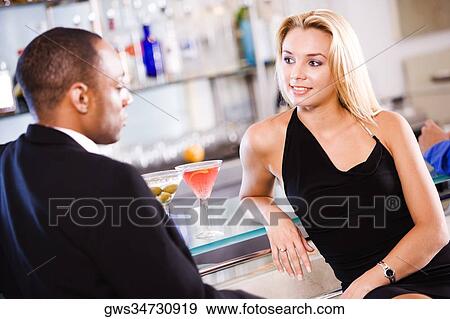 Young couple sitting at a bar counter View Large Photo Image Stock Photo - Young couple sitting at a bar counter. Fotosearch