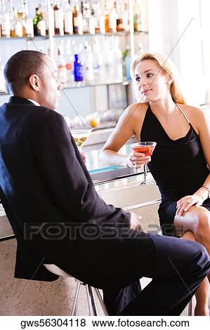 Young couple sitting at a bar counter View Large Photo Image Stock Photo - Young couple sitting at a bar counter. Fotosearch