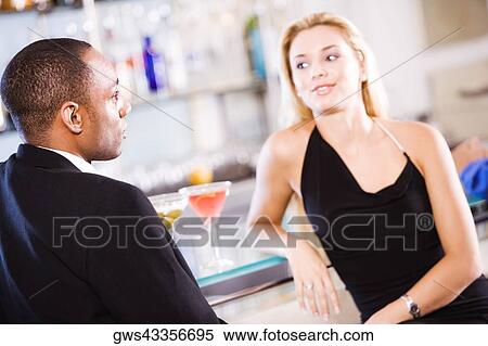 Young couple sitting at a bar counter View Large Photo Image Stock Photography - Young couple sitting at a bar counter. Fotosearch