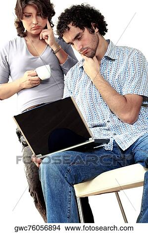 Young couple thinking while working on a laptop View Large Photo Image Picture - Young couple thinking while working on a laptop. Fotosearch