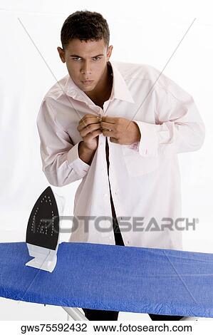 Stock Image - Young man buttoning his shirt. Fotosearch