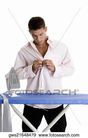 Young man buttoning his shirt View Large Photo Image Stock Photo - Young man buttoning his shirt. Fotosearch