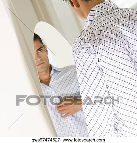 Young man looking at himself in a mirror View Large Photo Image Stock Photo - Young man looking at himself in a mirror. Fotosearch