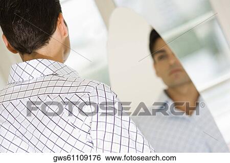 Young man looking at himself in a mirror View Large Photo Image Stock Photograph - Young man looking at himself in a mirror. Fotosearch