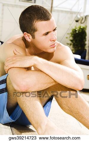 Young man sitting at the poolside View Large Photo Image Stock Image - Young man sitting at the poolside. Fotosearch
