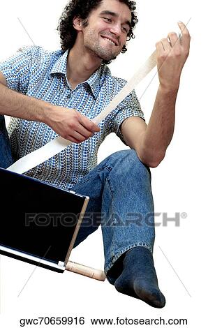 Young man sitting in front of a laptop holding a bill View Large Photo Image Stock Photograph - Young man sitting in front of a laptop holding a bill. Fotosearch