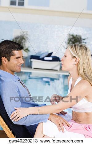 Young woman and a mid adult man sitting at the poolside View Large Photo Image Stock Image - Young woman and a mid adult man sitting at the poolside. Fotosearch