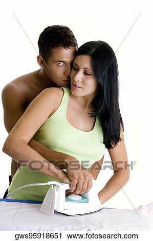 Young woman ironing with a young man embracing her from behind View Large Photo Image Stock Image - Young woman ironing with a young man embracing her from behind. Fotosearch