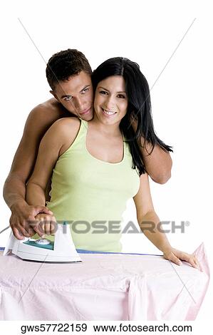 Young woman ironing with a young man embracing her from behind View Large Photo Image Stock Photo - Young woman ironing with a young man embracing her from behind. Fotosearch
