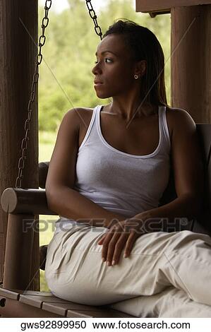 Stock Image - Young woman sitting on a swing looking serious. Fotosearch