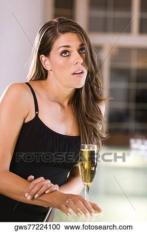 Young woman standing at a bar counter View Large Photo Image Stock Image - Young woman standing at a bar counter. Fotosearch