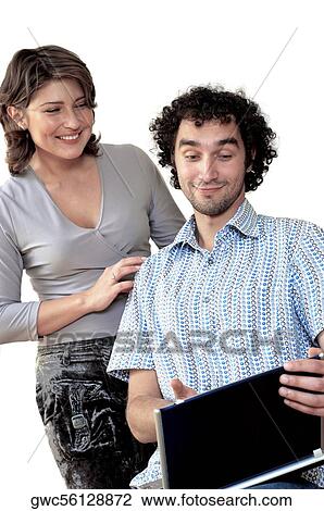 Young woman standing behind a young man working on a laptop View Large Photo Image Stock Image - Young woman standing behind a young man working on a laptop. Fotosearch
