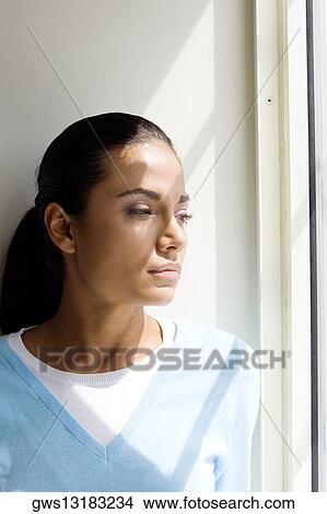 Young woman standing beside a window View Large Photo Image Picture - Young woman standing beside a window. Fotosearch
