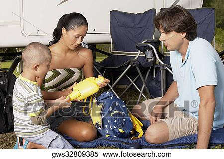 Boy holding a flashlight and sitting with his parents View Large Photo Image Stock Photography - Boy holding a flashlight and sitting with his parents. Fotosearch
