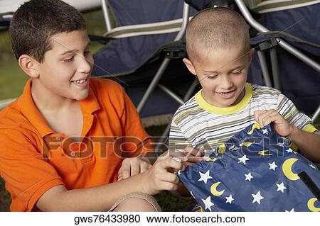 Boy sitting with his brother holding a bag and smiling View Large Photo Image Stock Image - Boy sitting with his brother holding a bag and smiling. Fotosearch