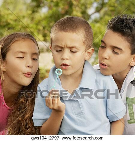 Close-up of a boy blowing bubbles with his brother and sister View Large Photo Image Stock Photo - Close-up of a boy blowing bubbles with his brother and sister. Fotosearch