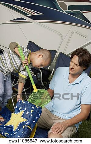 Close-up of a boy putting a butterfly net into a bag with his father looking at him View Large Photo Image Stock Photo - Close-up of a boy putting a butterfly net into a bag with his father looking at him. Fotosearch