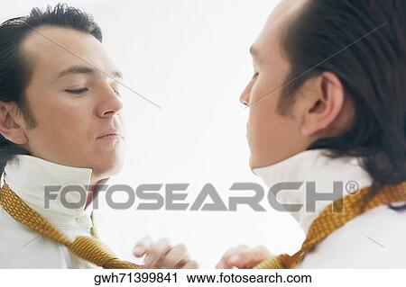 Close-up of a businessman adjusting his tie in front of a mirror View Large Photo Image Stock Image - Close-up of a businessman adjusting his tie in front of a mirror. Fotosearch
