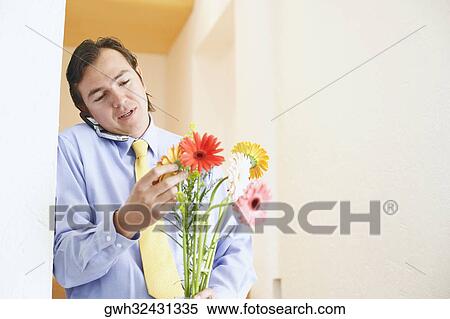 Close-up of a businessman talking on a mobile phone and holding a bunch of flowers View Large Photo Image Stock Photography - Close-up of a businessman talking on a mobile phone and holding a bunch of flowers. Fotosearch