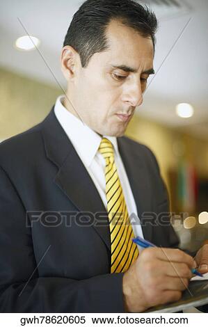 Stock Photography - Close-up of a businessman writing on a notepad. Fotosearch