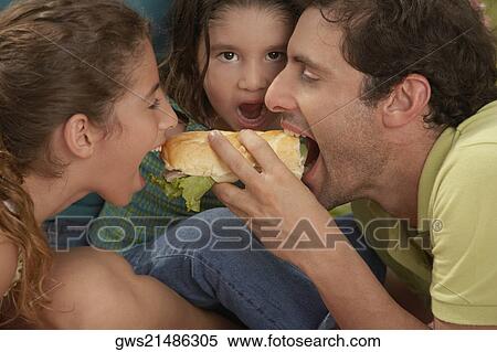 Stock Photography - Close-up of a family eating hot dogs. Fotosearch