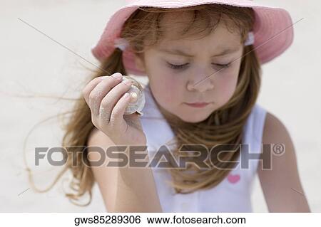 Close-up of a girl holding a seashell View Large Photo Image Stock Photograph - Close-up of a girl holding a seashell. Fotosearch