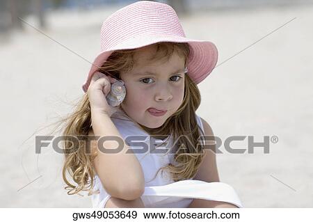 Stock Photo - Close-up of a girl listening to a conch shell. Fotosearch