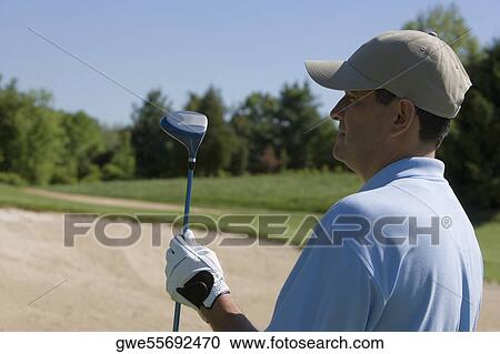 Stock Image - Close-up of a mature man holding a golf club. Fotosearch