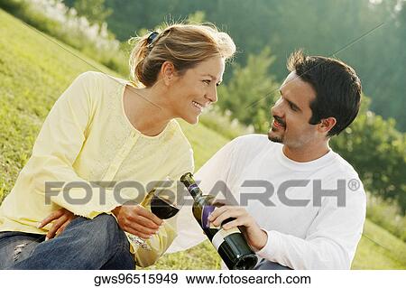 Stock Photo - Close-up of a mature man pouring wine into a young woman's glass. Fotosearch