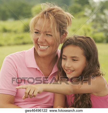 Stock Image - Close-up of a mature woman and her daughter pointing forwards. Fotosearch