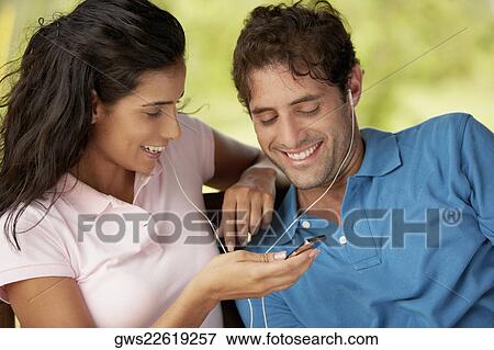 Close-up of a mid adult man and a young woman listening to an MP3 player View Large Photo Image Stock Photo - Close-up of a mid adult man and a young woman listening to an MP3 player. Fotosearch