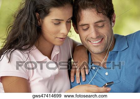 Close-up of a mid adult man and a young woman listening to an MP3 player View Large Photo Image Stock Photo - Close-up of a mid adult man and a young woman listening to an MP3 player. Fotosearch