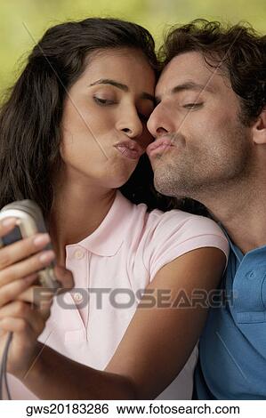 Stock Photograph - Close-up of a mid adult man and a young woman photographing themselves. Fotosearch