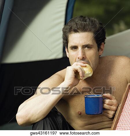 Close-up of a mid adult man holding a mug eating a piece of bread View Large Photo Image Stock Photo - Close-up of a mid adult man holding a mug eating a piece of bread. Fotosearch