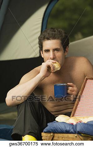 Close-up of a mid adult man holding a mug eating a piece of bread View Large Photo Image Stock Photography - Close-up of a mid adult man holding a mug eating a piece of bread. Fotosearch