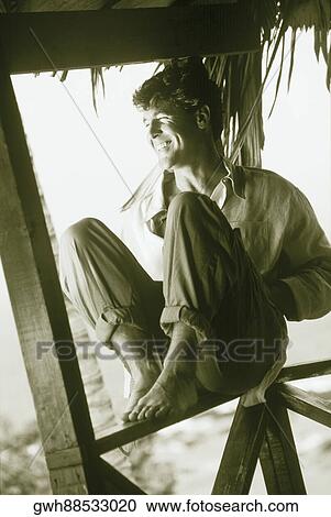 Close-up of a mid adult man sitting on a railing View Large Photo Image Stock Image - Close-up of a mid adult man sitting on a railing. Fotosearch