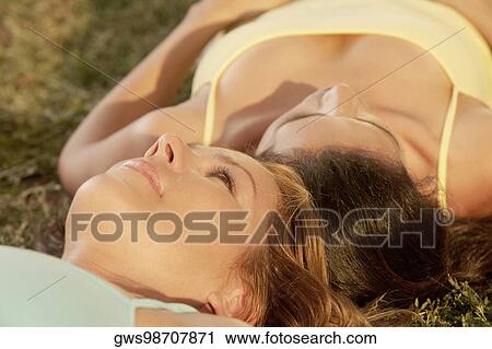 Close-up of a mid adult woman and a mature woman lying on the grass View Large Photo Image Stock Image - Close-up of a mid adult woman and a mature woman lying on the grass. Fotosearch