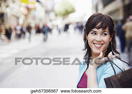 Stock Photo - Close-up of a mid adult woman holding a shopping bag . Fotosearch